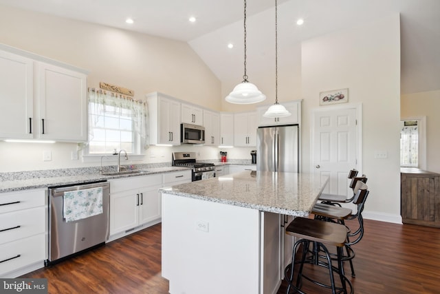 kitchen with a sink, white cabinetry, stainless steel appliances, high vaulted ceiling, and a breakfast bar area