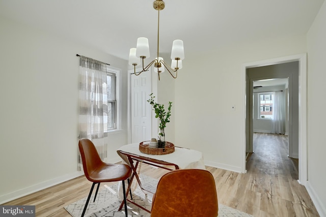 dining space with baseboards, an inviting chandelier, and light wood-style floors