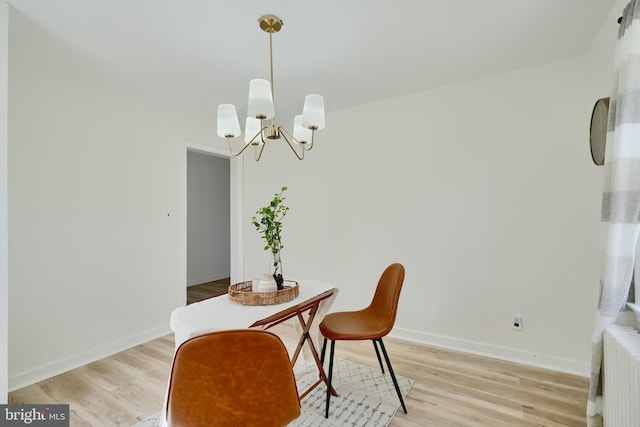 dining space featuring baseboards, a notable chandelier, and light wood-style flooring