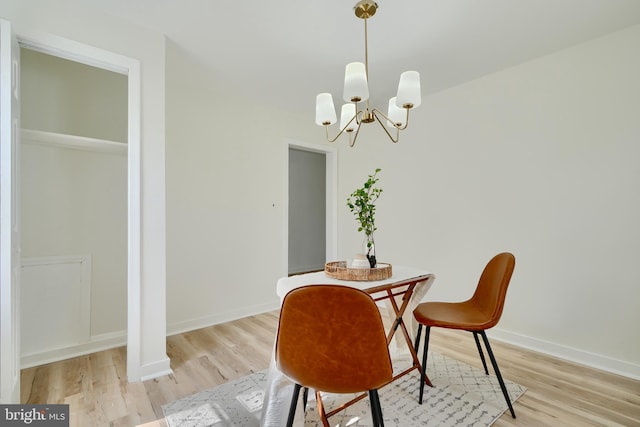 dining room featuring light wood-type flooring, baseboards, and a notable chandelier