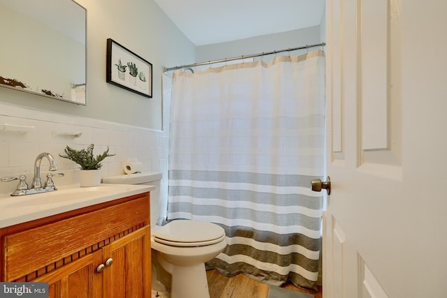 bathroom with wood finished floors, toilet, vanity, a shower with curtain, and tile walls