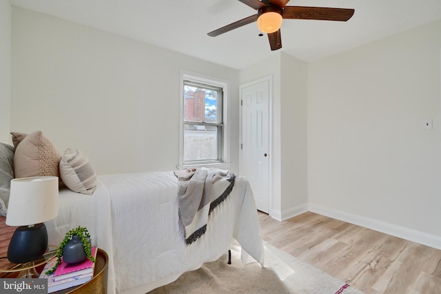bedroom with light wood-type flooring, a ceiling fan, and baseboards