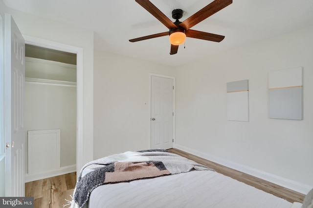 bedroom with ceiling fan, baseboards, wood finished floors, and a closet