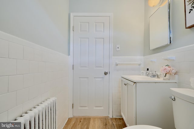 bathroom featuring tile walls, toilet, wainscoting, and radiator