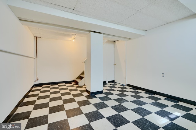 finished below grade area with light floors, rail lighting, baseboards, and stairs