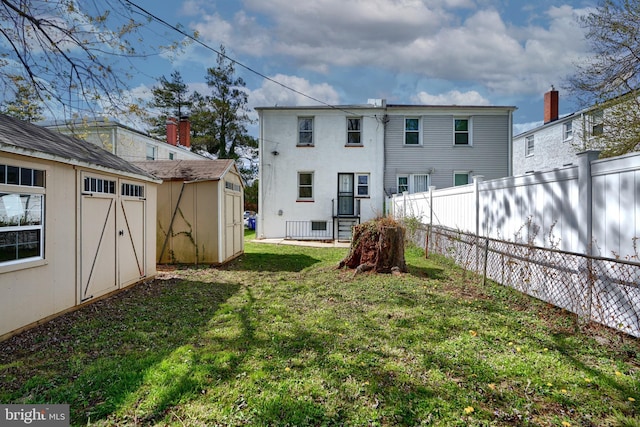 rear view of house featuring fence, an outbuilding, a yard, and a shed