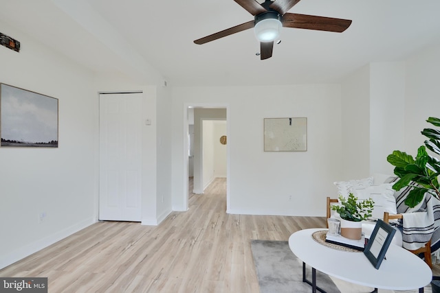 living area featuring ceiling fan, baseboards, and light wood-style flooring