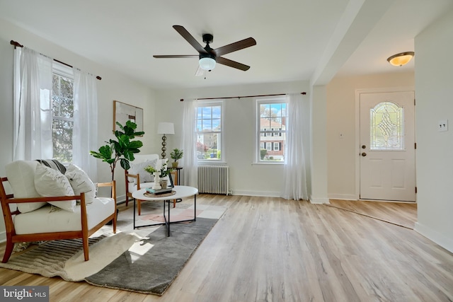 sitting room featuring a ceiling fan, baseboards, radiator heating unit, and wood finished floors