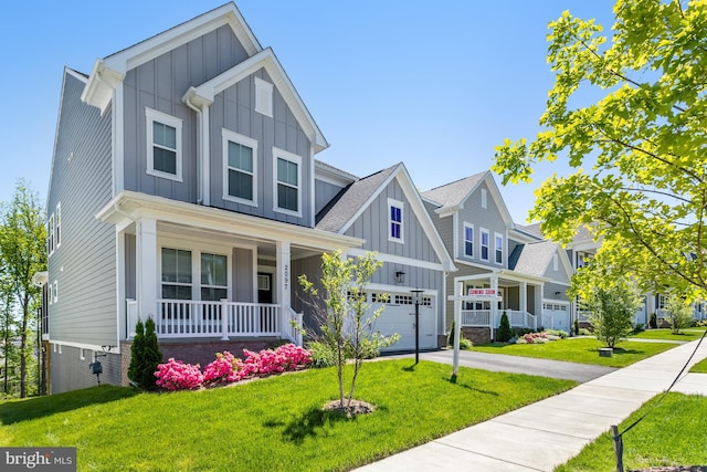 craftsman-style house featuring board and batten siding, covered porch, a front yard, a garage, and concrete driveway