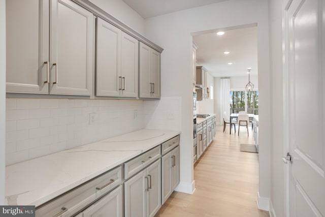 interior space featuring light stone countertops, light wood-style floors, recessed lighting, backsplash, and gray cabinetry