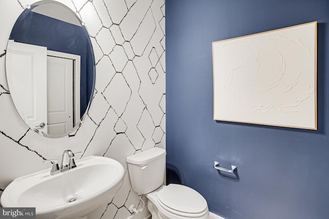 half bath with baseboards, a sink, and toilet