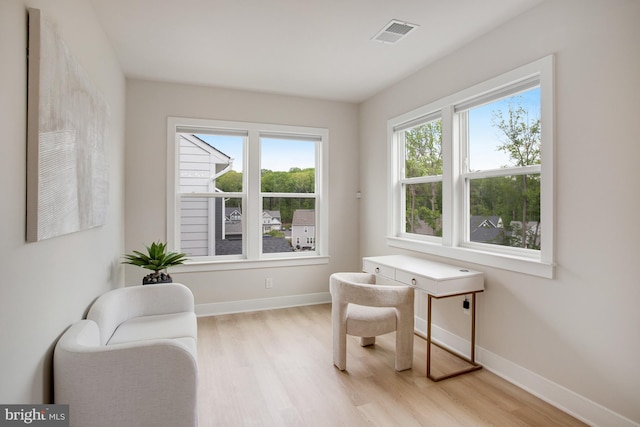 sitting room featuring baseboards, light wood finished floors, and visible vents