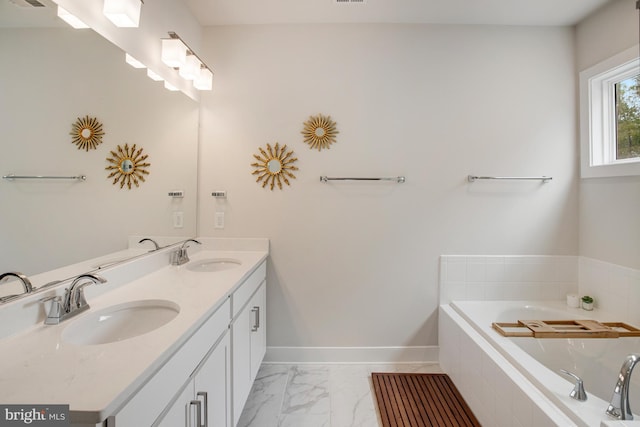 full bathroom with double vanity, a sink, marble finish floor, and a garden tub
