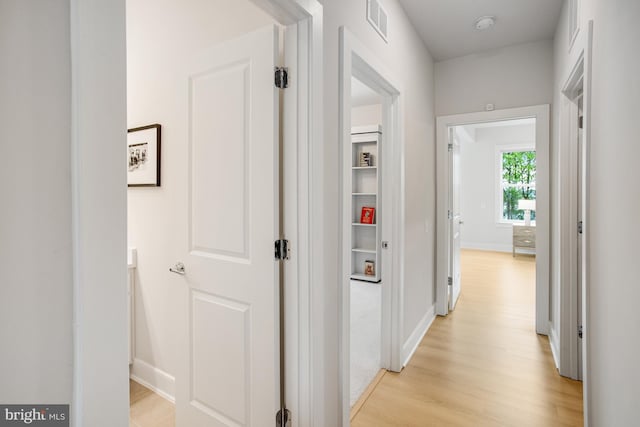 hallway featuring baseboards, visible vents, and light wood-type flooring