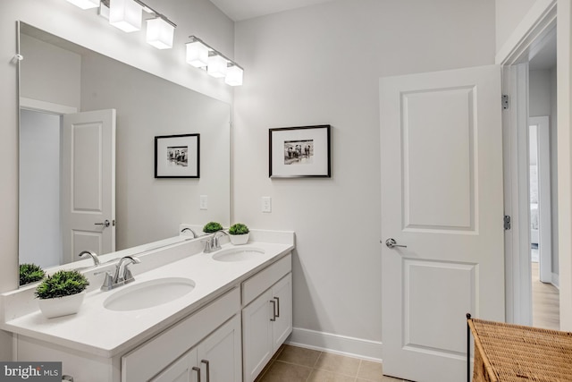 bathroom with double vanity, baseboards, a sink, and tile patterned flooring