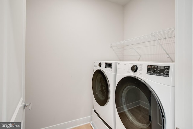 clothes washing area featuring laundry area, washer and clothes dryer, and baseboards