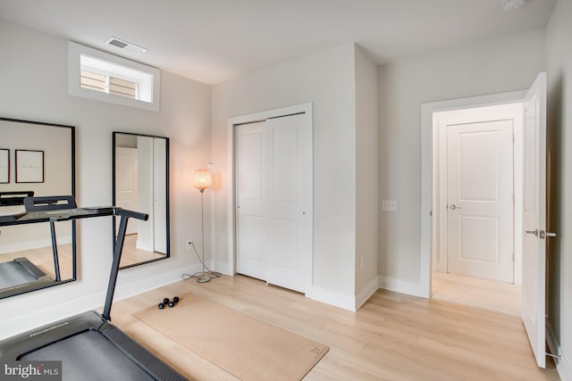 workout area featuring baseboards, visible vents, and light wood-style floors