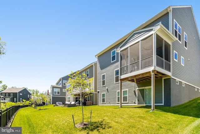 rear view of property with a lawn, a residential view, and a sunroom