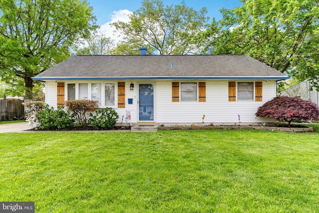 ranch-style home featuring fence and a front lawn