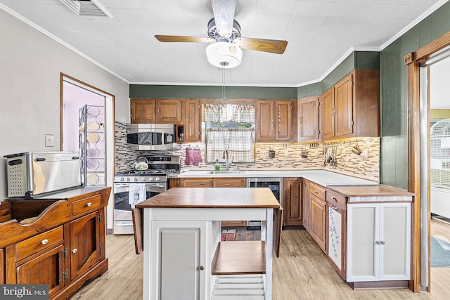 kitchen featuring ornamental molding, a kitchen island, stainless steel appliances, and light wood finished floors