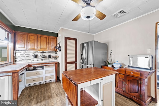 kitchen featuring decorative backsplash, stainless steel refrigerator with ice dispenser, dark wood-style floors, and visible vents