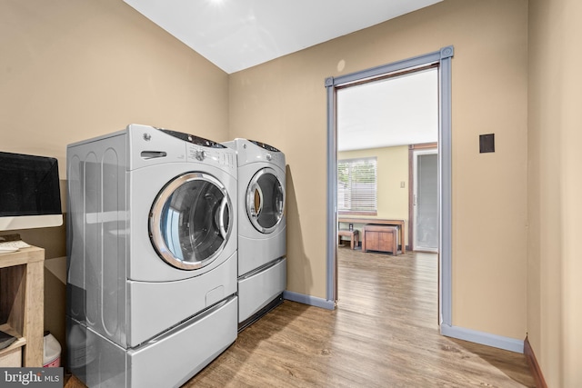washroom with independent washer and dryer, laundry area, baseboards, and wood finished floors