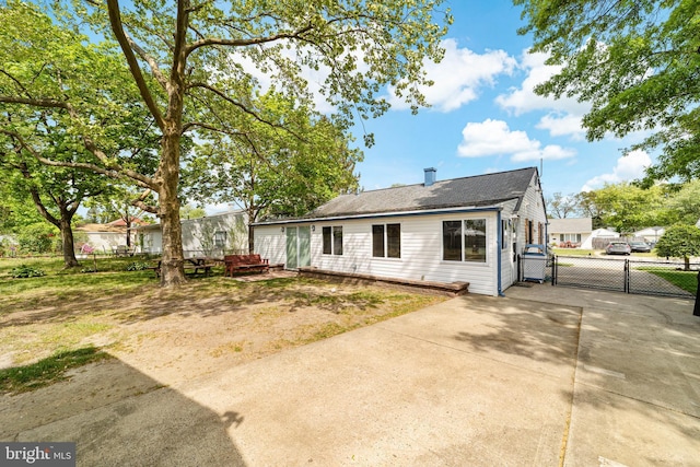 rear view of property featuring fence, driveway, and a gate