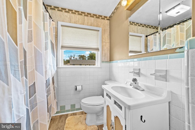 bathroom with vanity, toilet, tile walls, curtained shower, and wood finished floors