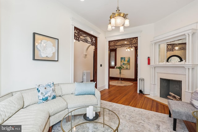 1231 Girard St NW, Washington, DC 20009 - living area with baseboards, an inviting chandelier, radiator heating unit, a fireplace with flush hearth, and wood finished floors