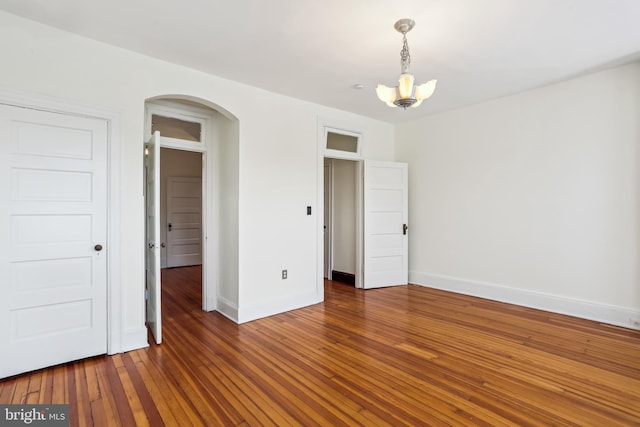 1231 Girard St NW, Washington, DC 20009 - unfurnished bedroom with baseboards, arched walkways, an inviting chandelier, and hardwood / wood-style flooring