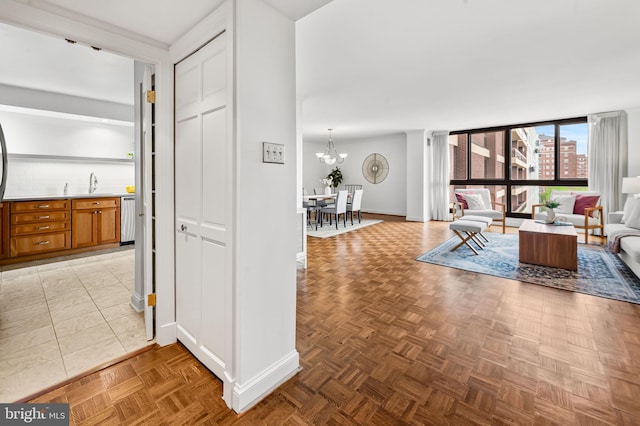 hall featuring baseboards, a chandelier, and a sink