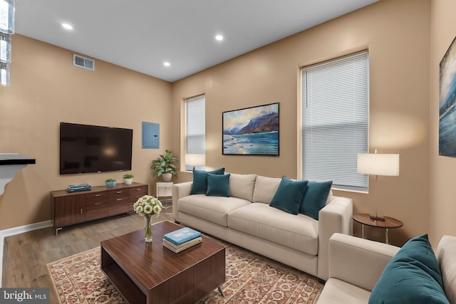 living room featuring electric panel, visible vents, recessed lighting, wood finished floors, and baseboards