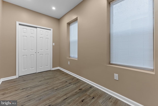 unfurnished bedroom featuring wood finished floors, baseboards, a closet, and recessed lighting