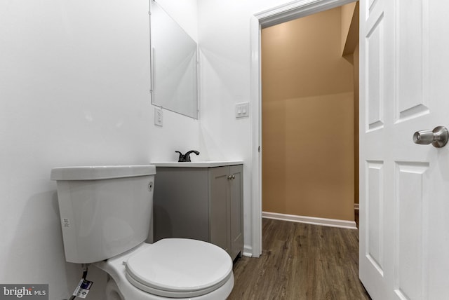 bathroom with toilet, wood finished floors, vanity, and baseboards