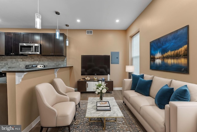 living room with electric panel, visible vents, recessed lighting, wood finished floors, and baseboards