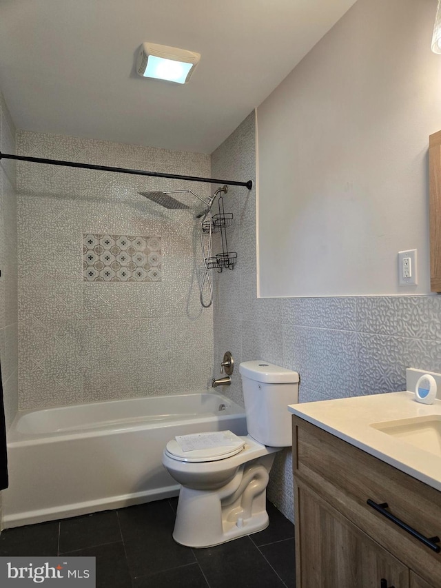 bathroom with shower / bathtub combination, vanity, tile patterned flooring, toilet, and tile walls