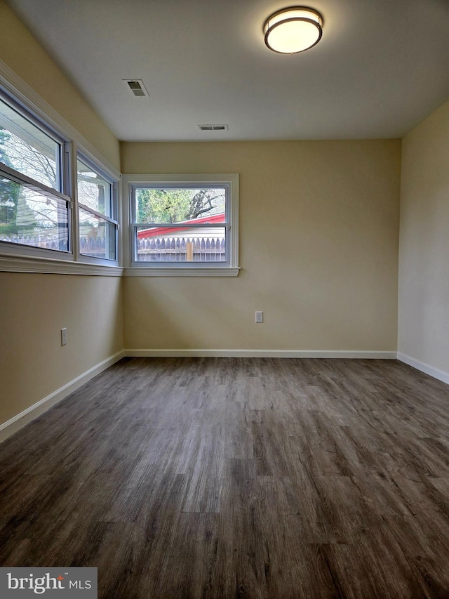 unfurnished room featuring visible vents, baseboards, and wood finished floors