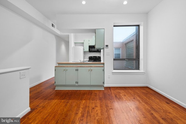 1773 Swann St NW, Washington, DC 20009 - kitchen with green cabinets, black microwave, freestanding refrigerator, dark wood-style floors, and recessed lighting
