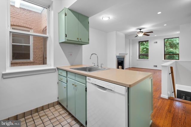 1773 Swann St NW, Washington, DC 20009 - kitchen featuring dishwasher, a peninsula, a ceiling fan, a warm lit fireplace, and light countertops