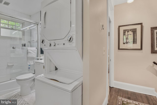 bathroom featuring estacked washer and dryer, toilet, wood finished floors, and baseboards