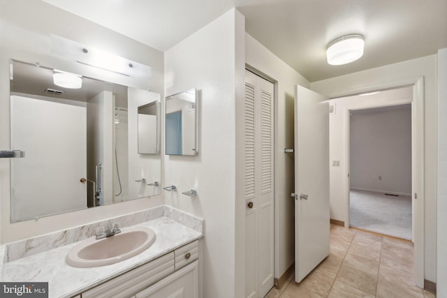 bathroom with a closet, vanity, tile patterned flooring, and visible vents