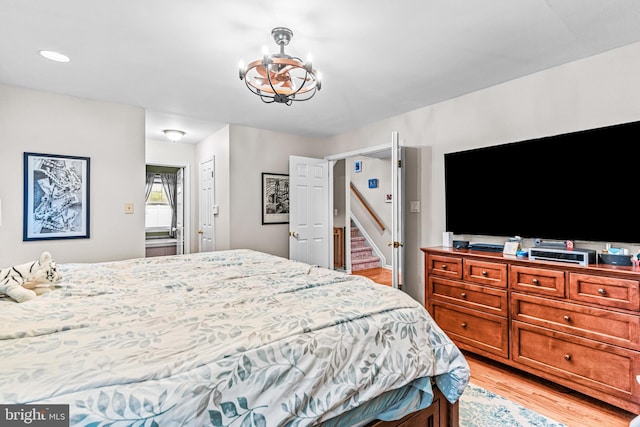 bedroom with light wood finished floors and a notable chandelier