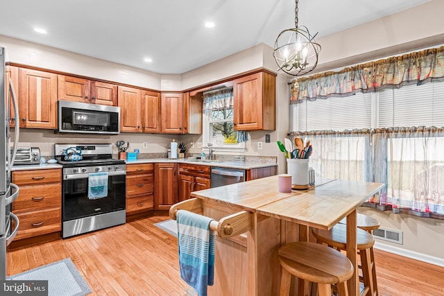 kitchen featuring a sink, light wood-style flooring, brown cabinets, and stainless steel appliances