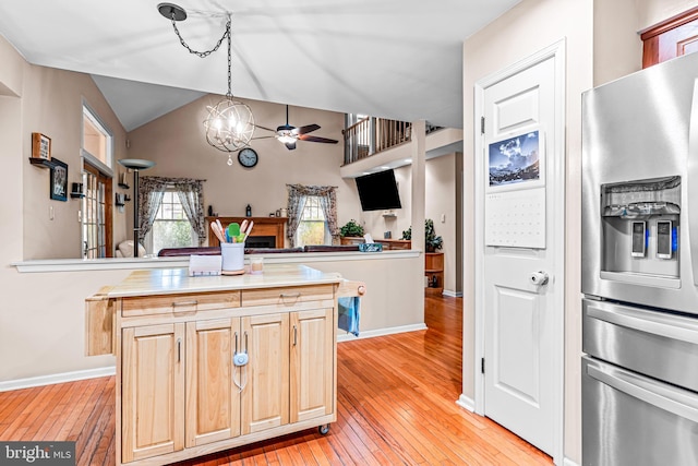 kitchen with stainless steel fridge with ice dispenser, light brown cabinets, vaulted ceiling, light wood-style flooring, and ceiling fan with notable chandelier