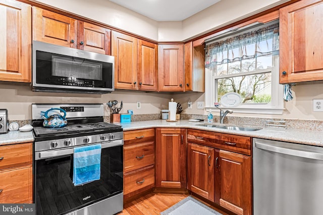 kitchen featuring brown cabinetry, light countertops, a sink, and appliances with stainless steel finishes