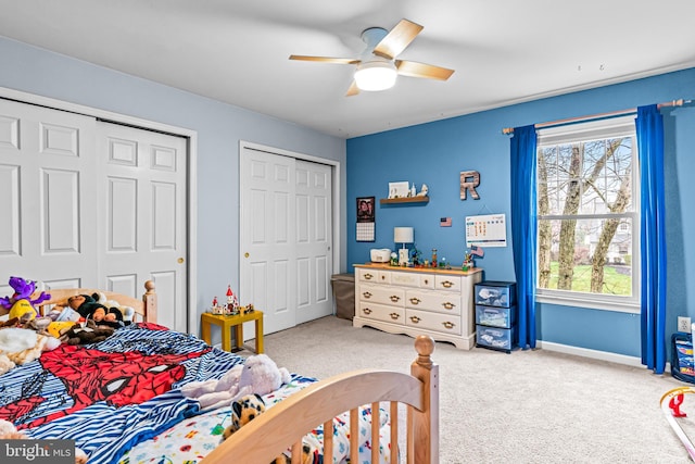 carpeted bedroom featuring baseboards, a ceiling fan, and multiple closets