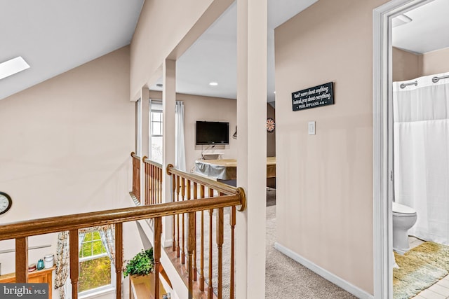 corridor with carpet floors, baseboards, an upstairs landing, and plenty of natural light