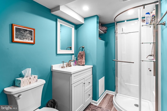 bathroom featuring a shower stall, vanity, toilet, wood finished floors, and baseboards