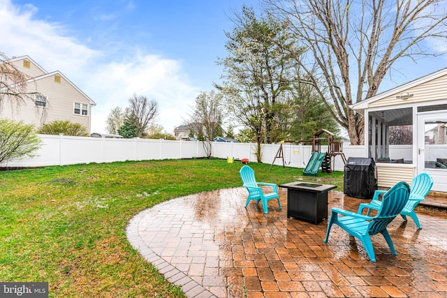 view of patio featuring a fenced backyard, a playground, an outdoor fire pit, and a sunroom