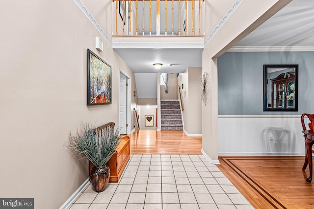 entrance foyer featuring light tile patterned floors, baseboards, a towering ceiling, and stairs